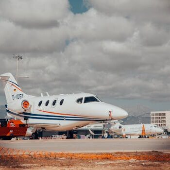 优选服务包 – 机场时刻 Ready for departure Premium Select Package – Ready for departure A private jet stationed on an airport tarmac with cloudy skies and mountains in the background.