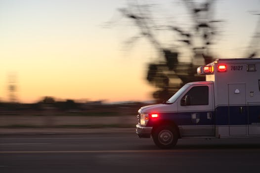 救护车在黄昏的城市街道疾驰 Ambulance racing down city street at dusk.